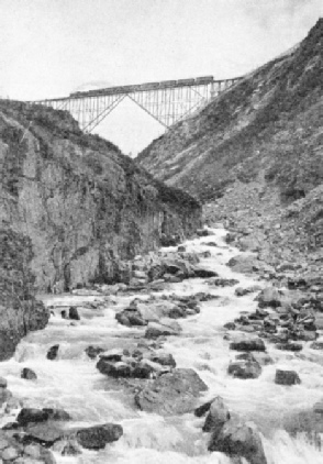 A TRAIN OF SEVEN COACHES crossing a cantilever bridge on the White Pass and Yukon Railway