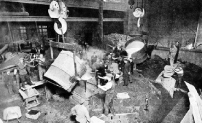 TWO LADLES OF MOLTEN BRONZE pour the metal into the mould of a large propeller