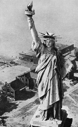 OVER 300 FEET ABOVE THE GROUND, the torch held in the right hand of the figure of Liberty is reached by a staircase inside the colossal monument