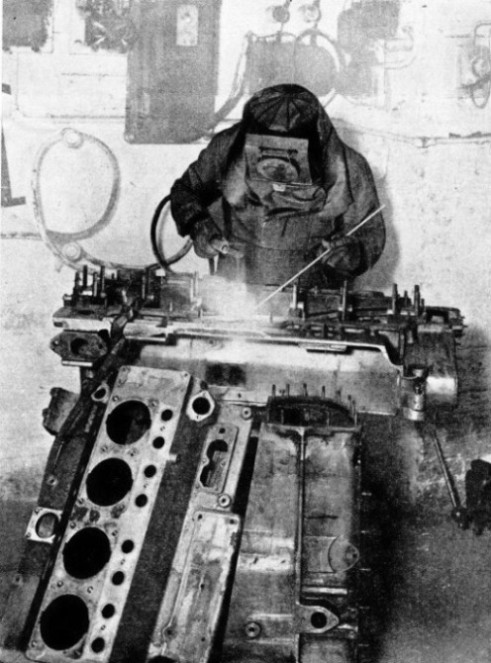 AN ELECTRIC ARC WELDER repairing a broken bearing in an aluminium crankcase of a motor vehicle