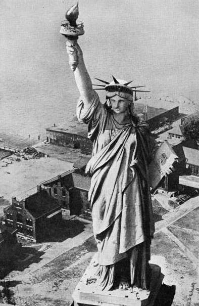 OVER 300 FEET ABOVE THE GROUND, the torch held in the right hand of the figure of Liberty is reached by a staircase inside the colossal monument