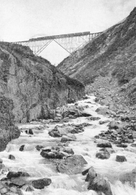 A TRAIN OF SEVEN COACHES crossing a cantilever bridge on the White Pass and Yukon Railway